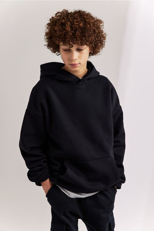 A child wearing a white fleece pullover hoodie with a hood and a kangaroo pocket.
