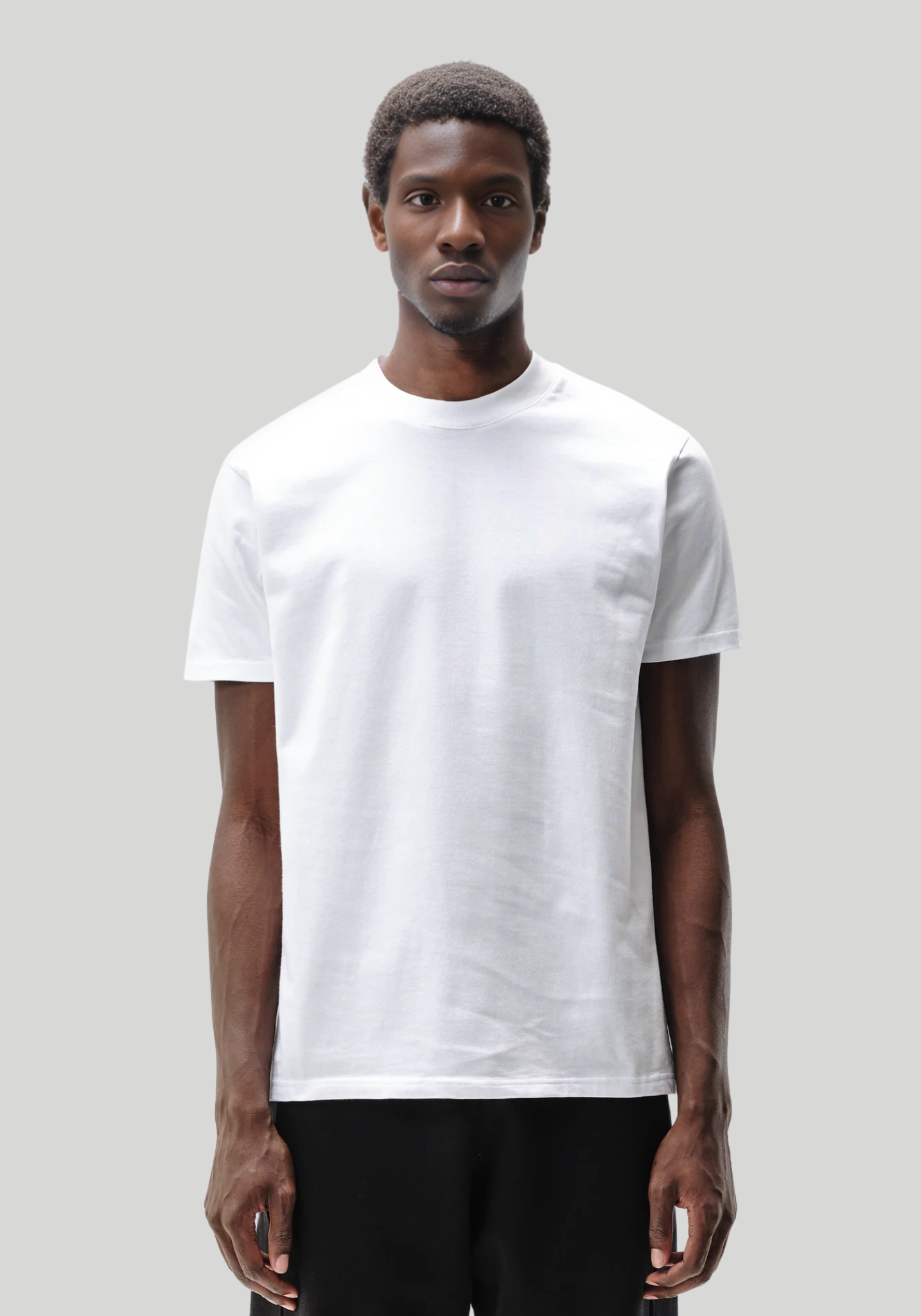 Man wearing a plain white t-shirt against a light gray background